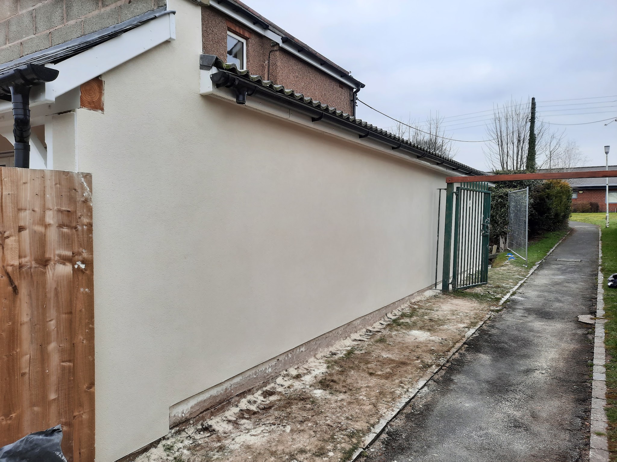 An exterior side wall freshly rendered in a smooth cream finish